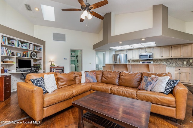 living room featuring dark wood-style floors, a skylight, visible vents, a ceiling fan, and washing machine and dryer