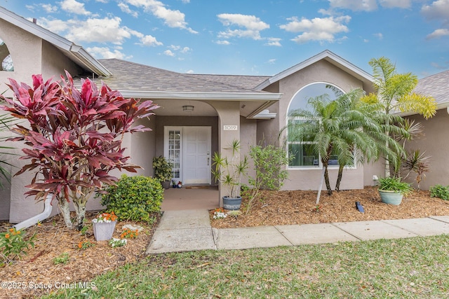 doorway to property with roof with shingles and stucco siding