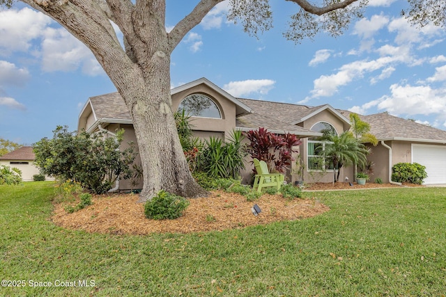 view of front of property with a garage, a front lawn, and stucco siding