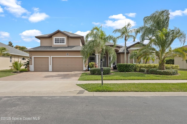 view of front of home featuring a garage, driveway, a front yard, and stucco siding