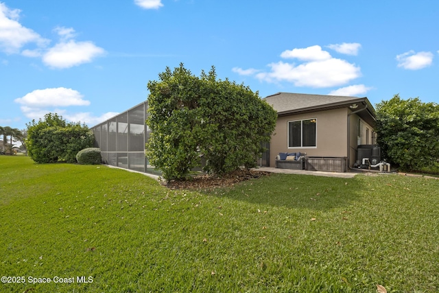 back of property featuring a yard, glass enclosure, a patio, and stucco siding