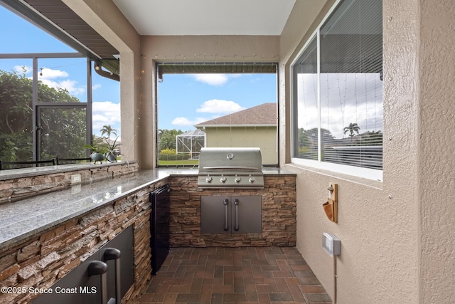 view of patio with exterior kitchen, a lanai, and a grill