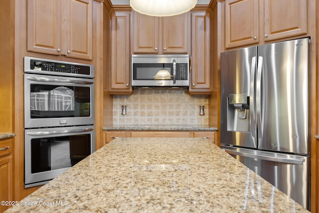 kitchen featuring appliances with stainless steel finishes, decorative backsplash, and light stone counters