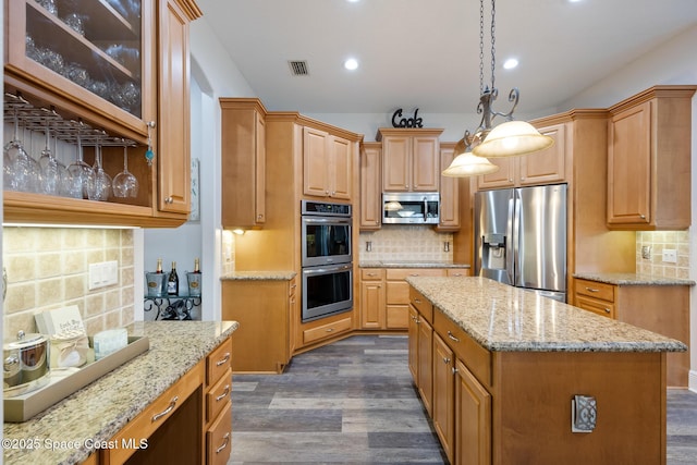 kitchen with tasteful backsplash, visible vents, a kitchen island, appliances with stainless steel finishes, and dark wood-type flooring