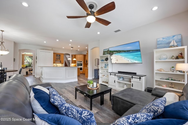 living room featuring visible vents, arched walkways, wood finished floors, stairs, and recessed lighting