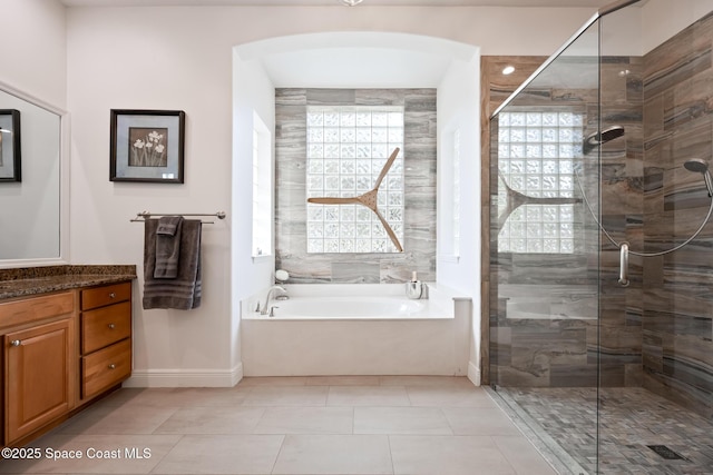 bathroom with a garden tub, vanity, a shower stall, baseboards, and tile patterned floors