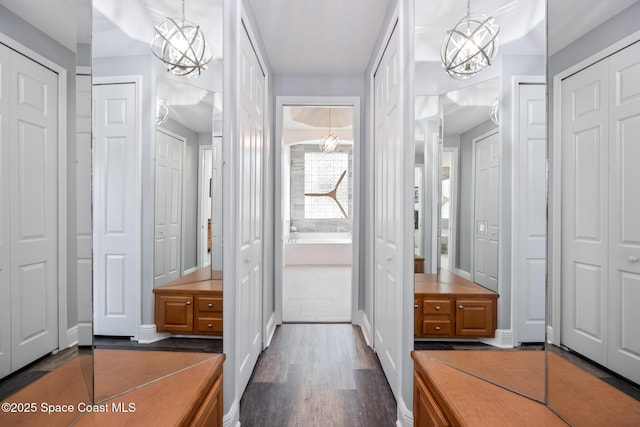 interior space featuring a chandelier, dark wood-type flooring, and baseboards