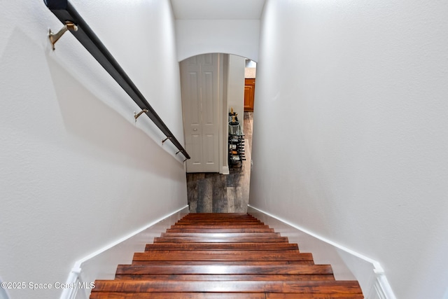 stairway with arched walkways and wood finished floors