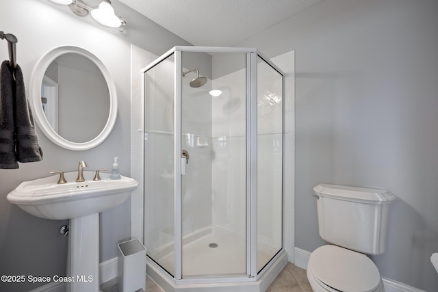 bathroom featuring a stall shower, baseboards, and toilet