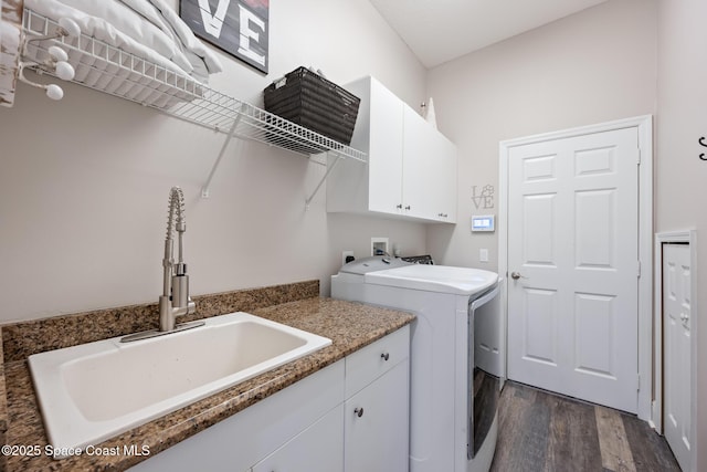 clothes washing area with cabinet space, dark wood-type flooring, a sink, and washing machine and clothes dryer