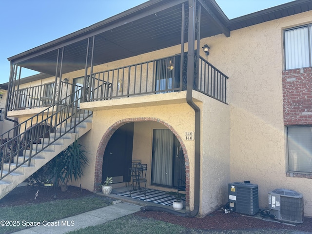 view of exterior entry with stucco siding and central AC unit