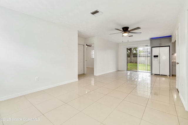 empty room featuring baseboards, visible vents, a ceiling fan, and light tile patterned flooring