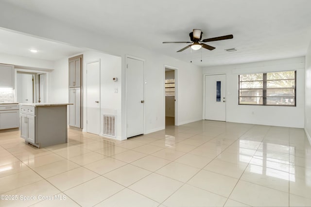 interior space with ceiling fan, light tile patterned flooring, visible vents, and baseboards