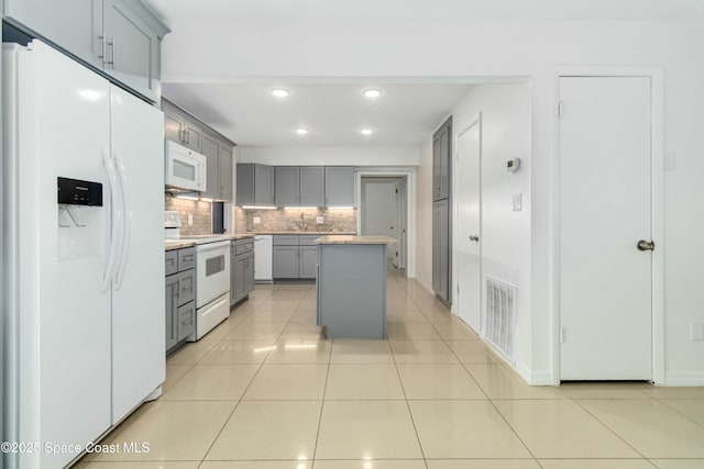 kitchen featuring white appliances, light tile patterned floors, visible vents, and gray cabinetry