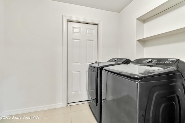 washroom with laundry area, baseboards, washing machine and clothes dryer, and light tile patterned floors