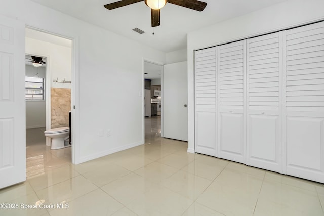 unfurnished bedroom with a closet, visible vents, ensuite bathroom, freestanding refrigerator, and light tile patterned flooring