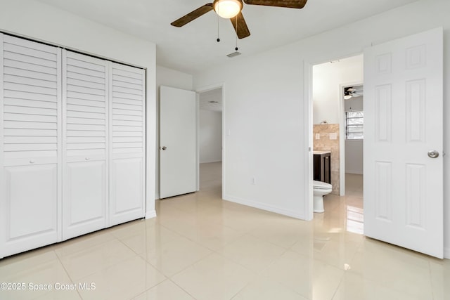 unfurnished bedroom featuring light tile patterned floors, ceiling fan, connected bathroom, baseboards, and a closet