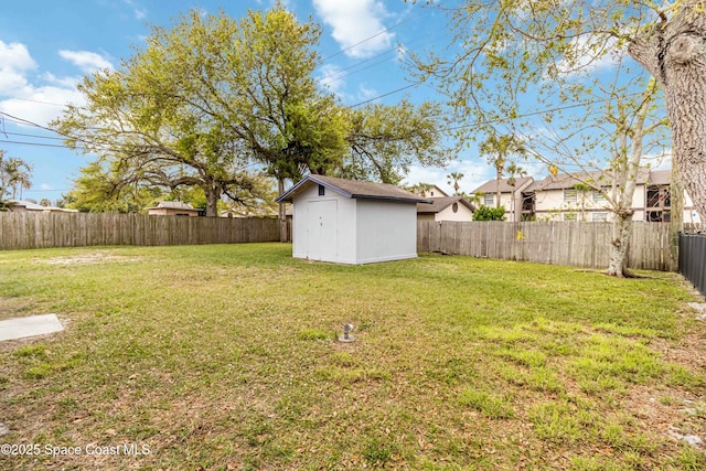 view of yard with a shed, a fenced backyard, and an outbuilding