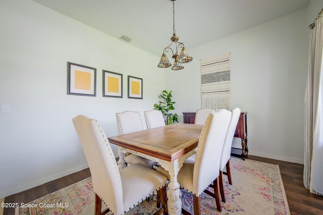 dining area featuring baseboards, wood finished floors, visible vents, and a notable chandelier