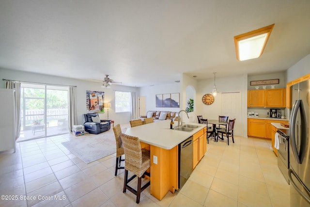 kitchen with appliances with stainless steel finishes, open floor plan, light countertops, and a sink