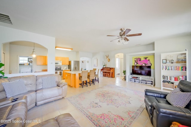 living room with arched walkways, ceiling fan, light tile patterned flooring, and visible vents