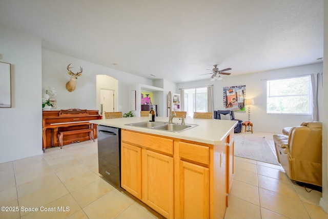 kitchen with light tile patterned floors, a sink, open floor plan, light countertops, and dishwasher