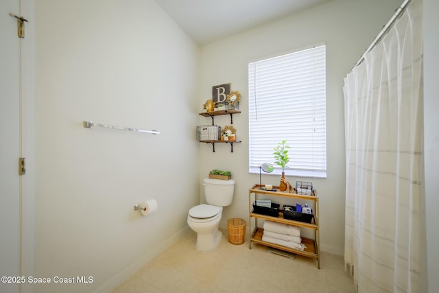 bathroom with toilet, a shower with curtain, and baseboards