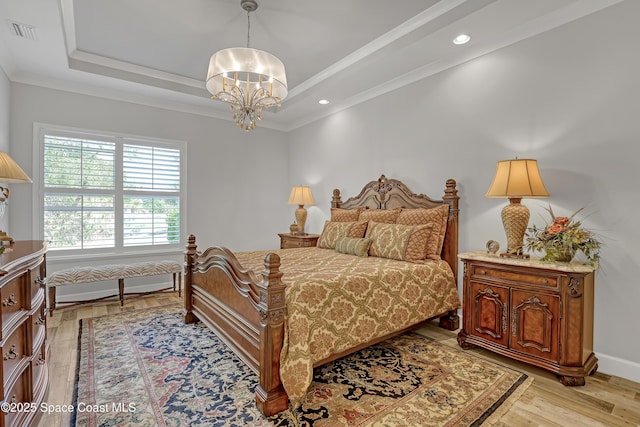 bedroom with visible vents, light wood finished floors, ornamental molding, a raised ceiling, and a notable chandelier