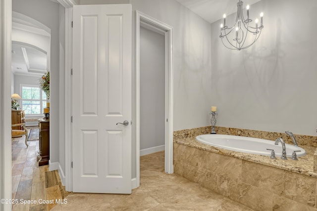 bathroom featuring a garden tub, a notable chandelier, and crown molding