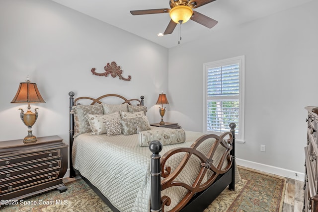 bedroom featuring baseboards, wood finished floors, and a ceiling fan