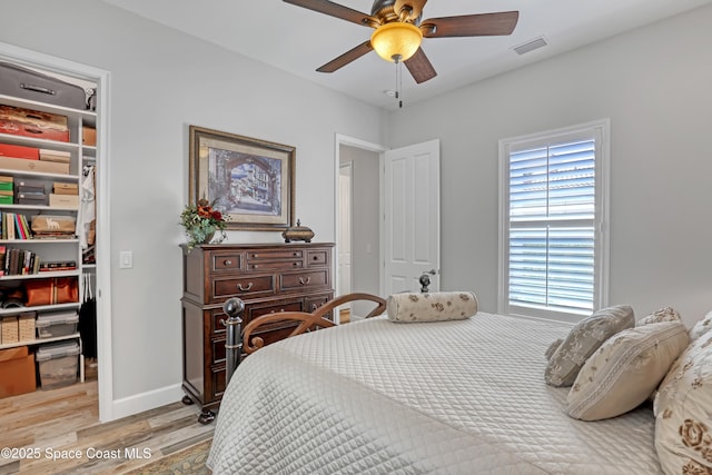 bedroom with visible vents, a walk in closet, a closet, light wood finished floors, and ceiling fan