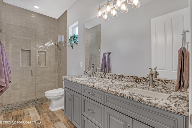 full bathroom featuring a tile shower, wood finished floors, and a sink