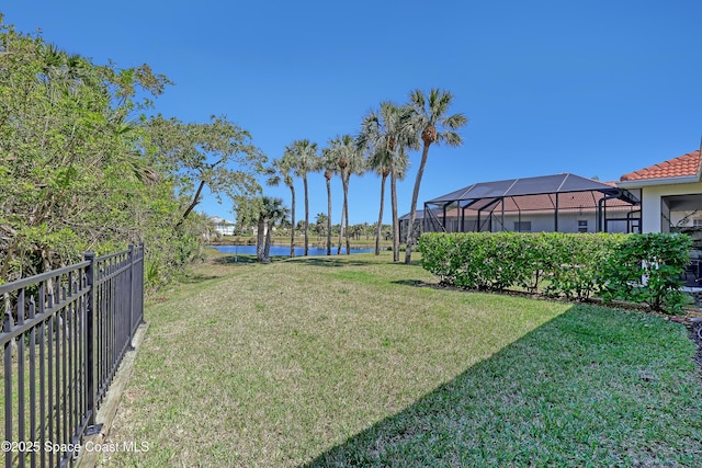 view of yard with glass enclosure, fence, and a water view