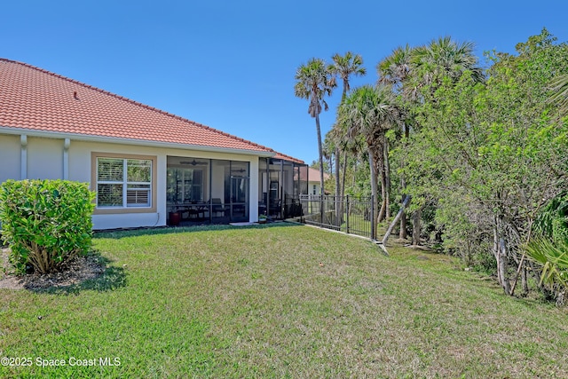 view of yard featuring a sunroom, ceiling fan, and fence