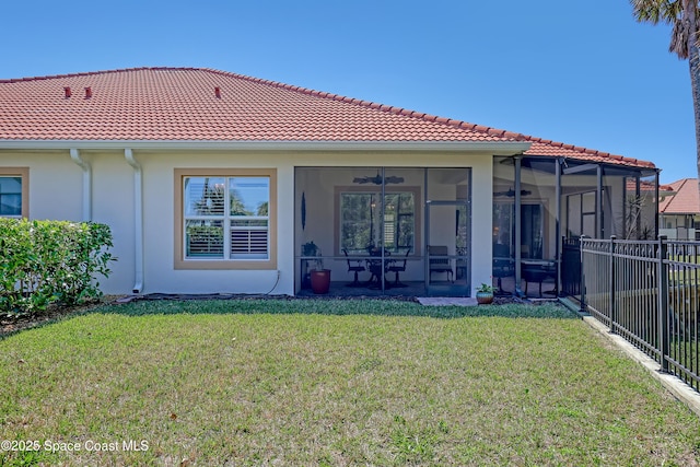 rear view of property featuring a ceiling fan, fence, a sunroom, stucco siding, and a lawn