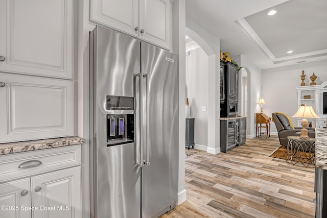 kitchen with open floor plan, light wood-type flooring, high end refrigerator, recessed lighting, and arched walkways