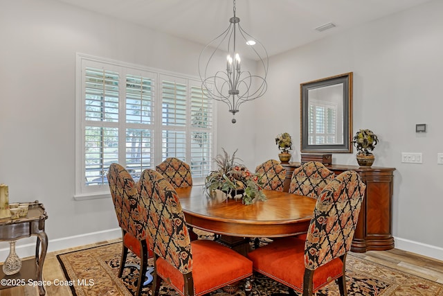 dining area with a notable chandelier, baseboards, visible vents, and wood finished floors