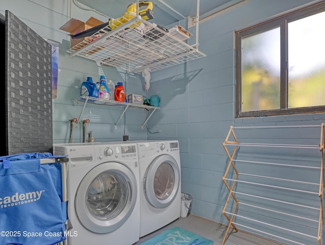 washroom featuring washing machine and dryer, laundry area, and concrete block wall