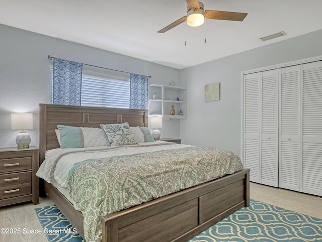 bedroom featuring a ceiling fan, light wood-style flooring, visible vents, and a closet