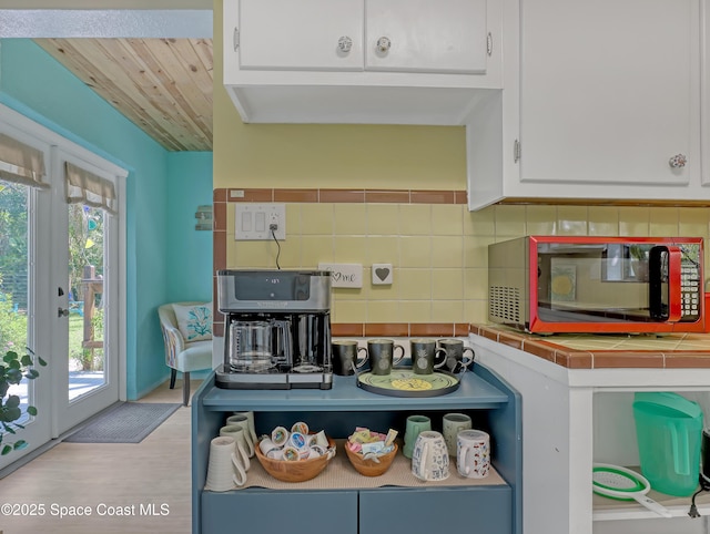 kitchen with tile counters, white cabinetry, backsplash, and wood finished floors