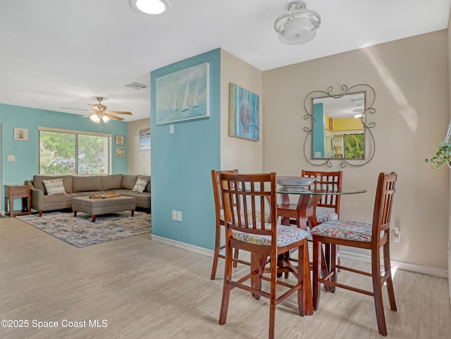 dining room featuring light wood-style flooring, visible vents, ceiling fan, and baseboards