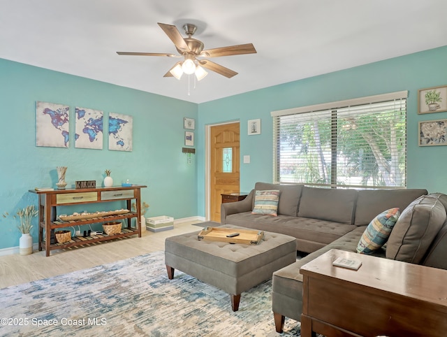 living room featuring ceiling fan, baseboards, and wood finished floors