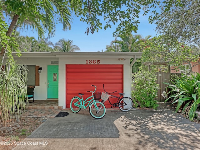 garage featuring driveway and fence