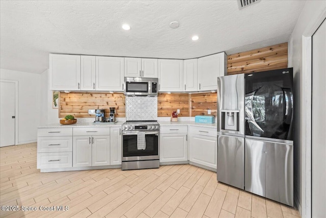 kitchen featuring light wood-style floors, white cabinetry, appliances with stainless steel finishes, and light countertops