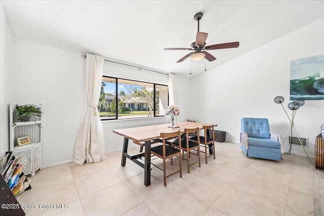 dining room with baseboards, ceiling fan, vaulted ceiling, a textured ceiling, and light tile patterned flooring