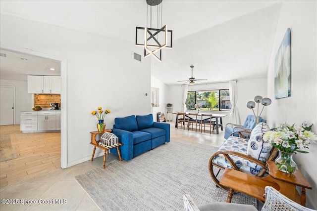 living room featuring a ceiling fan, visible vents, vaulted ceiling, and baseboards