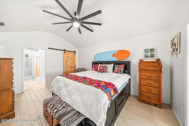 bedroom with lofted ceiling, ceiling fan, light wood finished floors, and a barn door