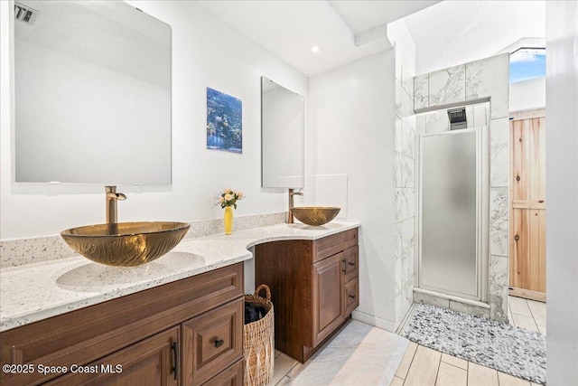 full bath featuring double vanity, a stall shower, a sink, and visible vents