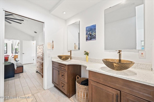 ensuite bathroom with double vanity, vaulted ceiling, a sink, and ensuite bathroom