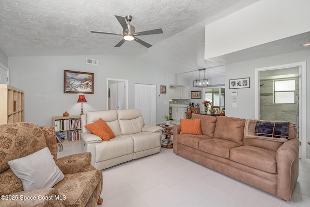 living area with lofted ceiling, a ceiling fan, visible vents, and a textured ceiling